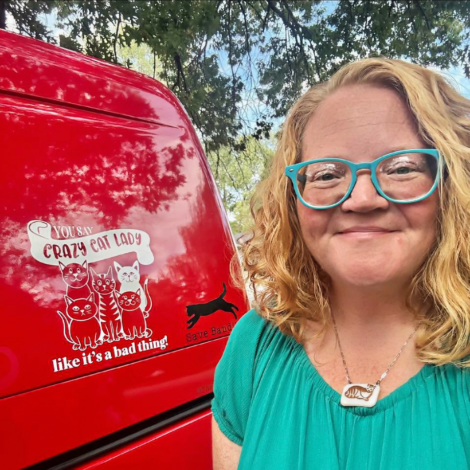 a photo of the board member, jill! they are standing to the right of a van with a decal of some cartoonish cats with the text \